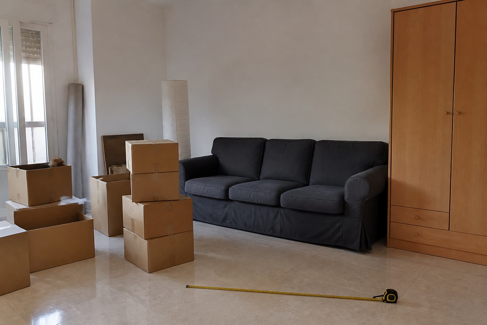 Salón con cajas, sofá y cinta métrica para estimar el volumen de una mudanza.
